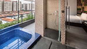 A modern bathroom with a glass shower enclosure, a blue-tiled bathtub, and a bed with a wooden headboard. - A Hotel Dickson, Stay From 9PM To 8AM (Singapore)
