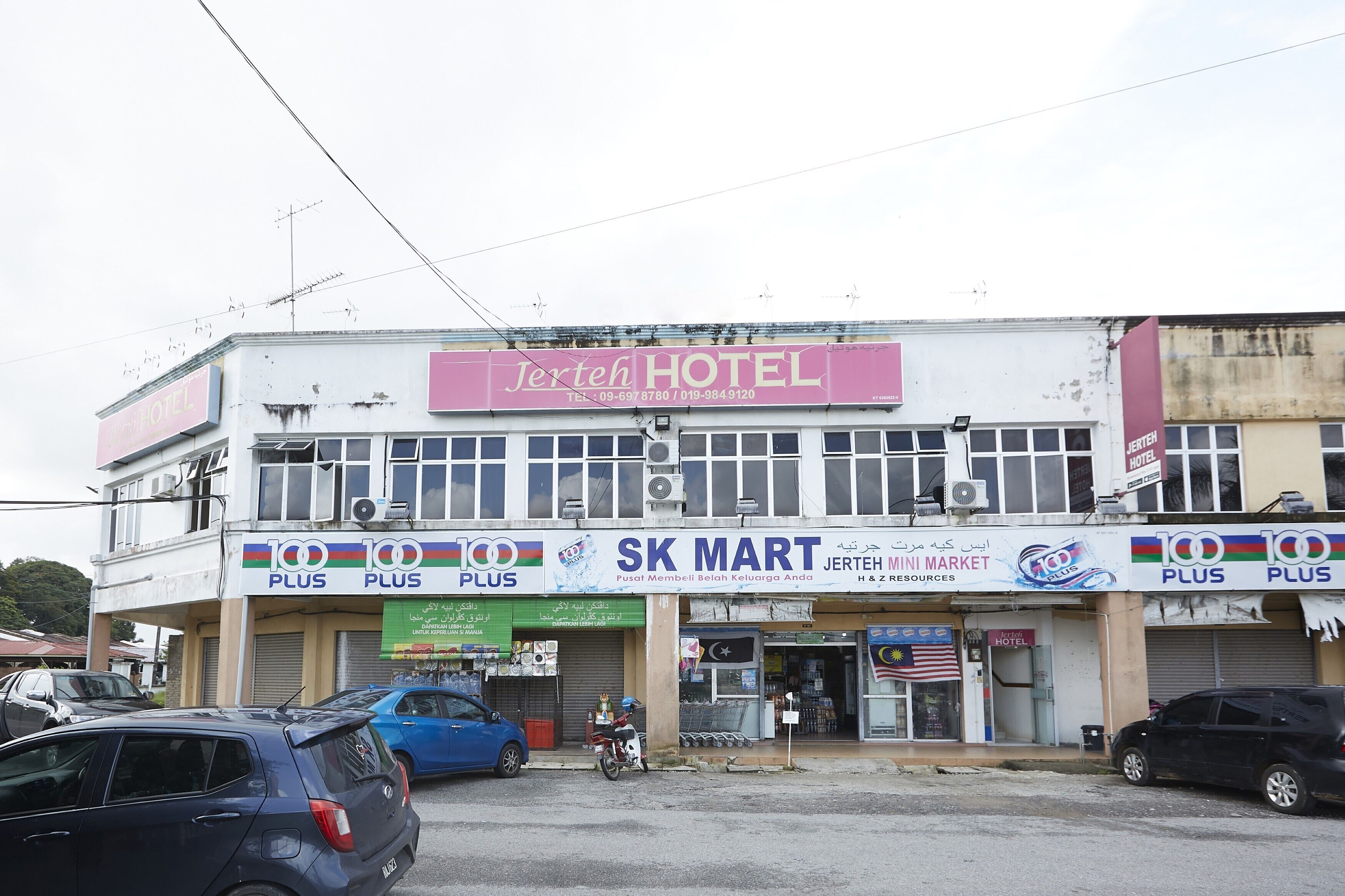 Un hotel con un cartel que dice "Jerteh Hotel" y una tienda en la planta baja con los rótulos "SK Mart" y "100 Plus".
