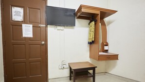 A room with a brown door, a flat-screen TV mounted on the wall, a wooden table, and a wooden cabinet with a mirror. - Jerteh Hotel, Terengganu (Jerteh)