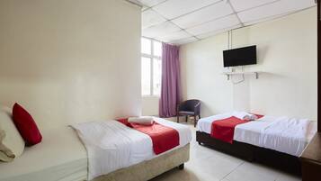 Habitación de hotel con dos camas, un televisor montado en la pared y una ventana con cortinas.