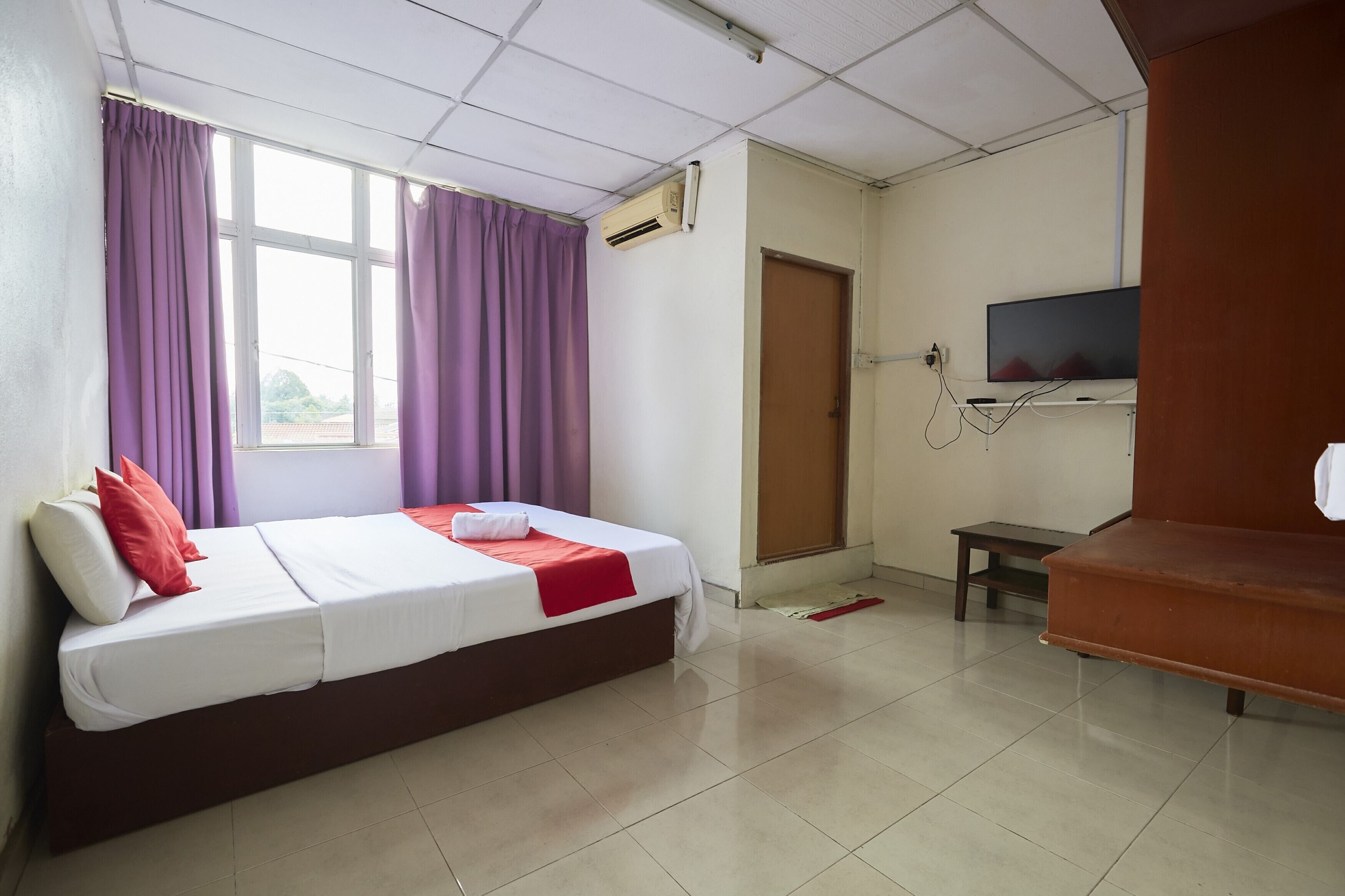 A hotel room with a bed, a TV, a small table, and a door.