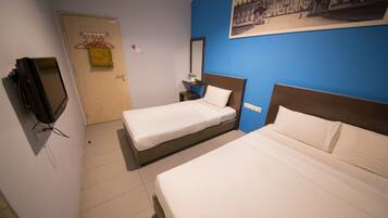 Habitación de hotel con dos camas individuales, televisor, una mesita pequeña y un espejo instalado en la pared.