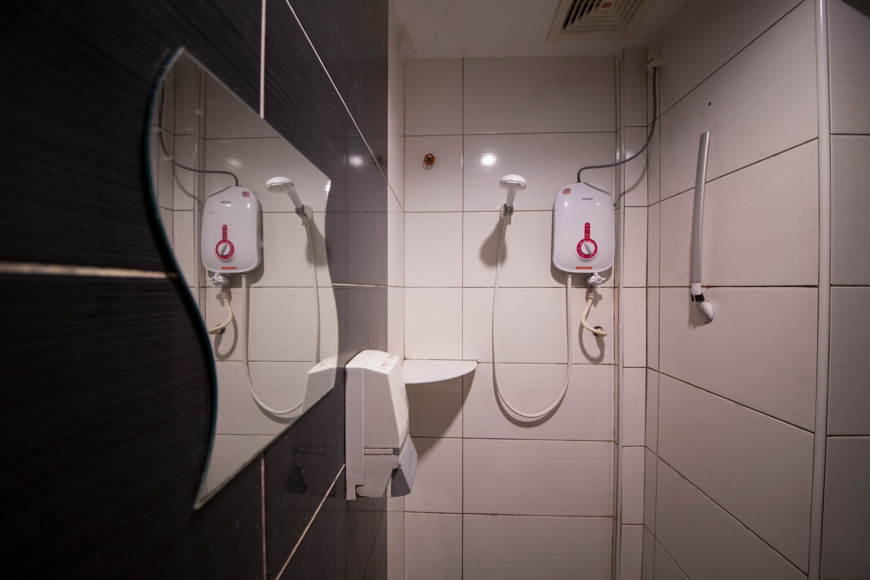 A bathroom with a mirror, two hand dryers, and a sink.