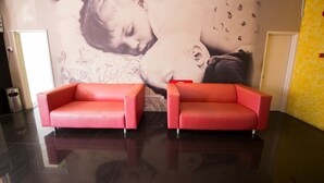 A lobby with two red sofas, a large wall mural, and a yellow patterned wall. - Golden Pearl Hotel Near Universiti Tun Hussein Onn Malaysia UTHM (Batu Pahat)