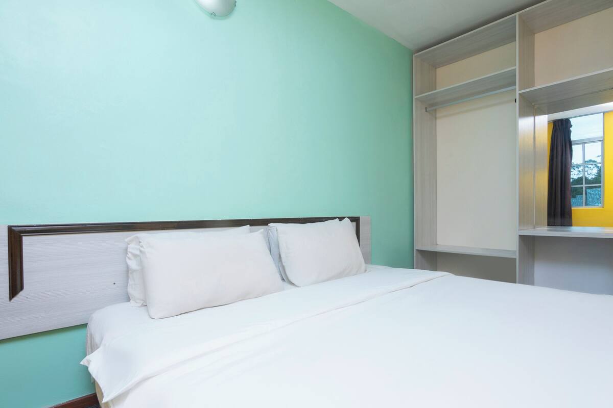 A bed with white bedding, a headboard, and a shelf unit with a window.