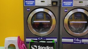 A laundromat with two 14kg washers, a free detergent & softener sign, and a Sondico SportsDirect.com advertisement. - Madani Hotel Cameron Highland (Tanah Rata)