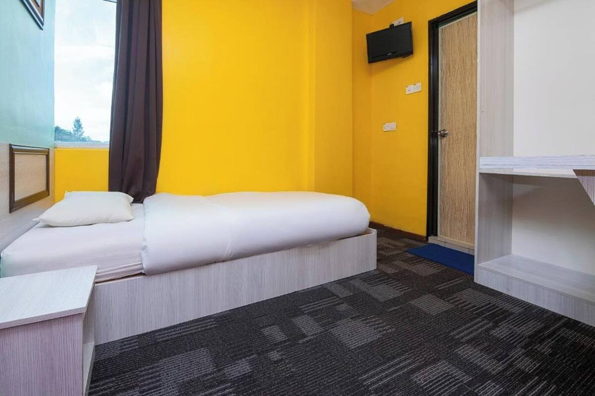 A hotel room with two beds, a TV, a door, and a small desk.