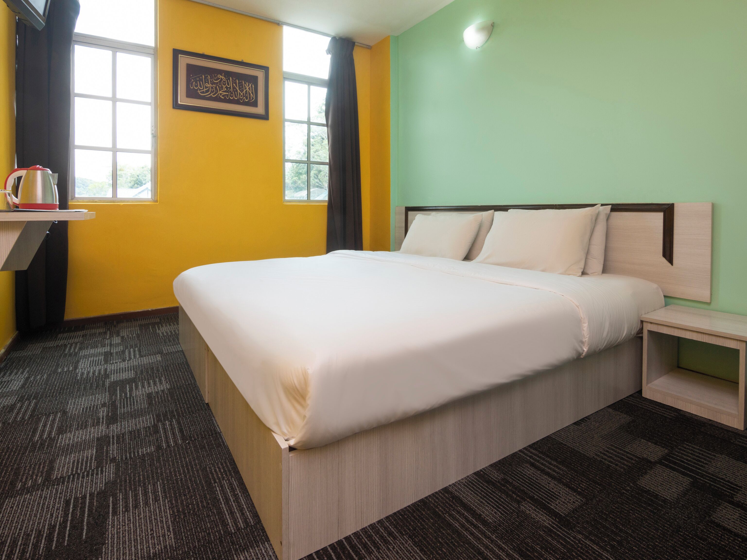 Quarto de hotel com cama, mesa de cabeceira, janela, moldura e cortina.