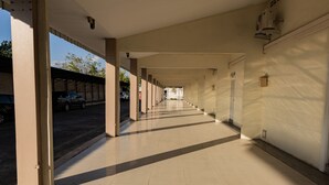 A long, covered corridor with a tiled floor, leading to a building entrance.