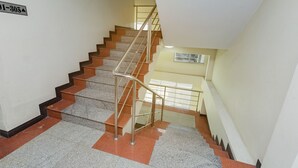 A multi-level interior with a staircase, handrails, and a sign indicating room numbers.