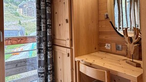 A wooden cabin with a large window, a wooden table, and a mirror.