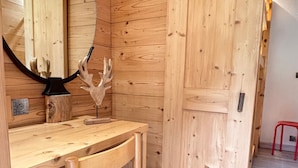 A wooden interior with a bench, a wall-mounted deer head decoration, and a red stool.