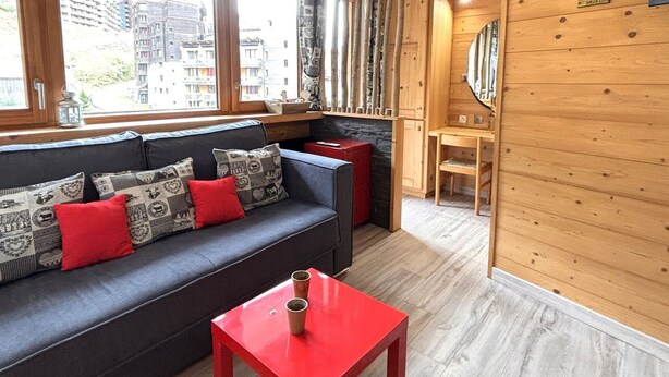 A cozy room with a sofa, a small table, and a view of buildings outside.
