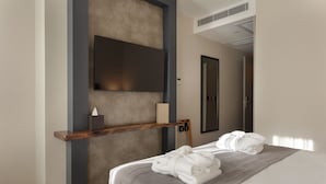 A modern hotel room with a large bed, a mounted TV, a wooden shelf with a tissue box, and a mirror.