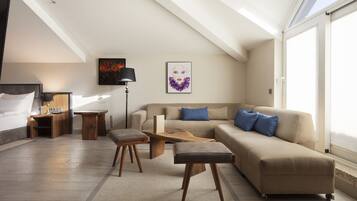 Una sala de estar moderna con sofá, mesa de centro, reposapiés, escritorio y cama.