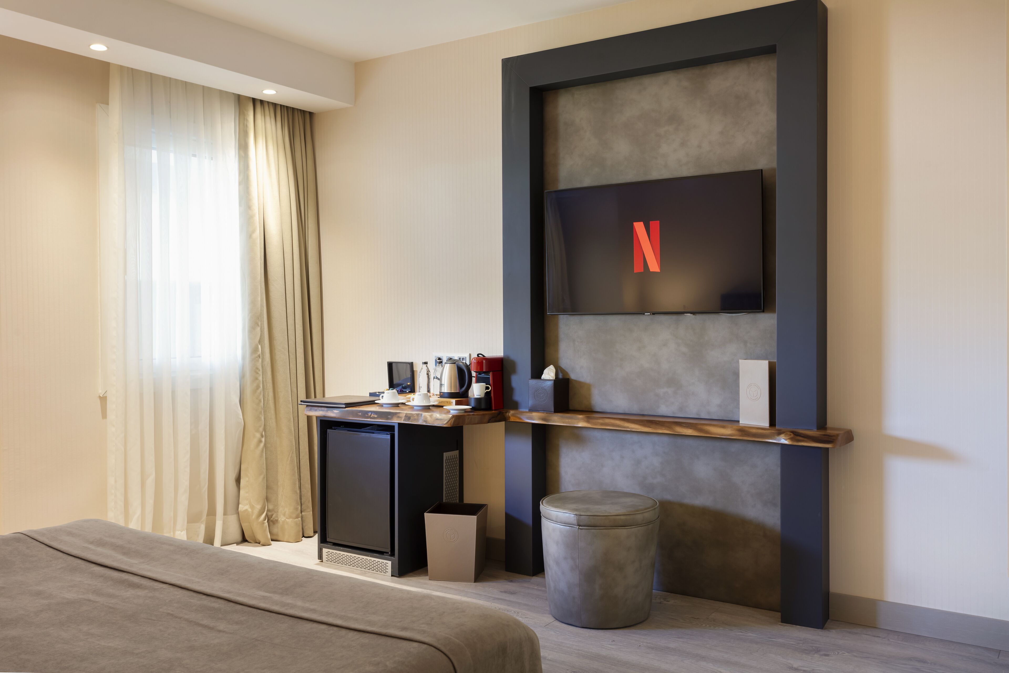 A modern hotel room with a bed, a desk, a television, and a small trash bin.