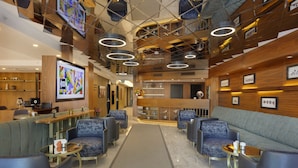 A modern lobby with a central reception desk, seating area, and a staircase.