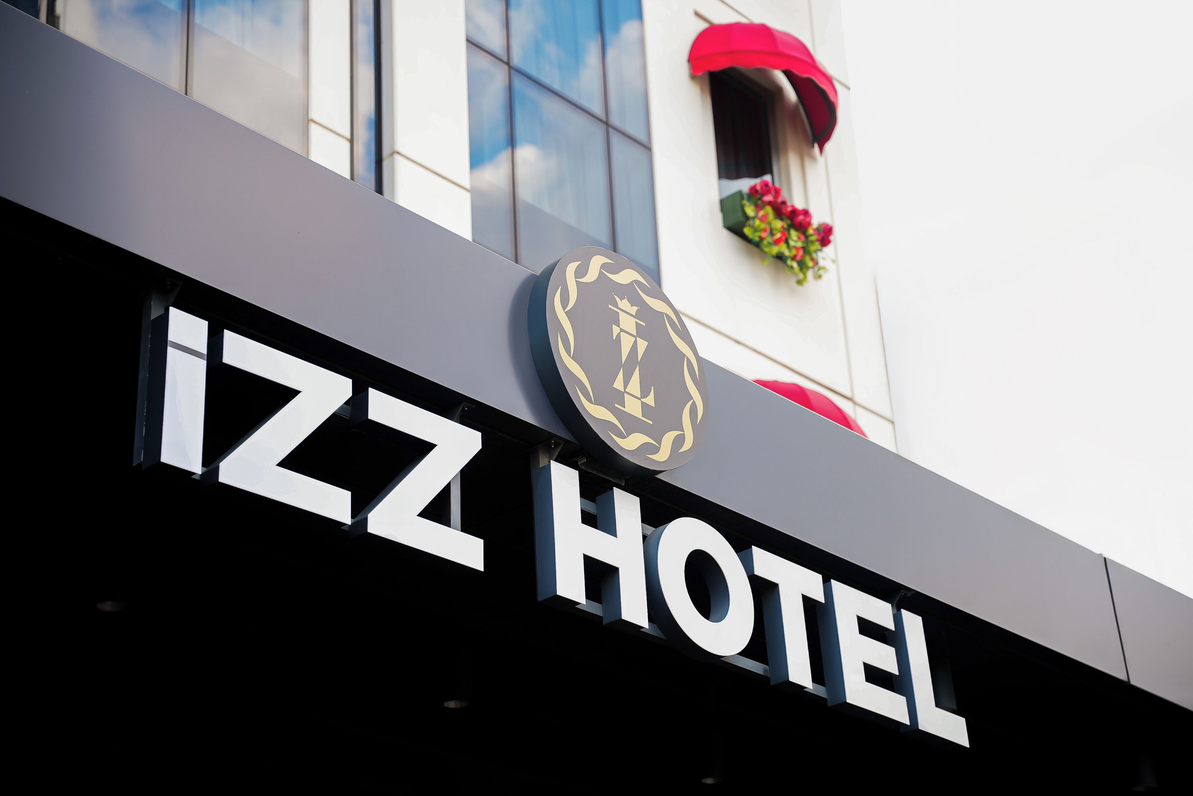 Ein Hotelschild mit dem Schriftzug "IZZ HOTEL" und einem Logo darüber.