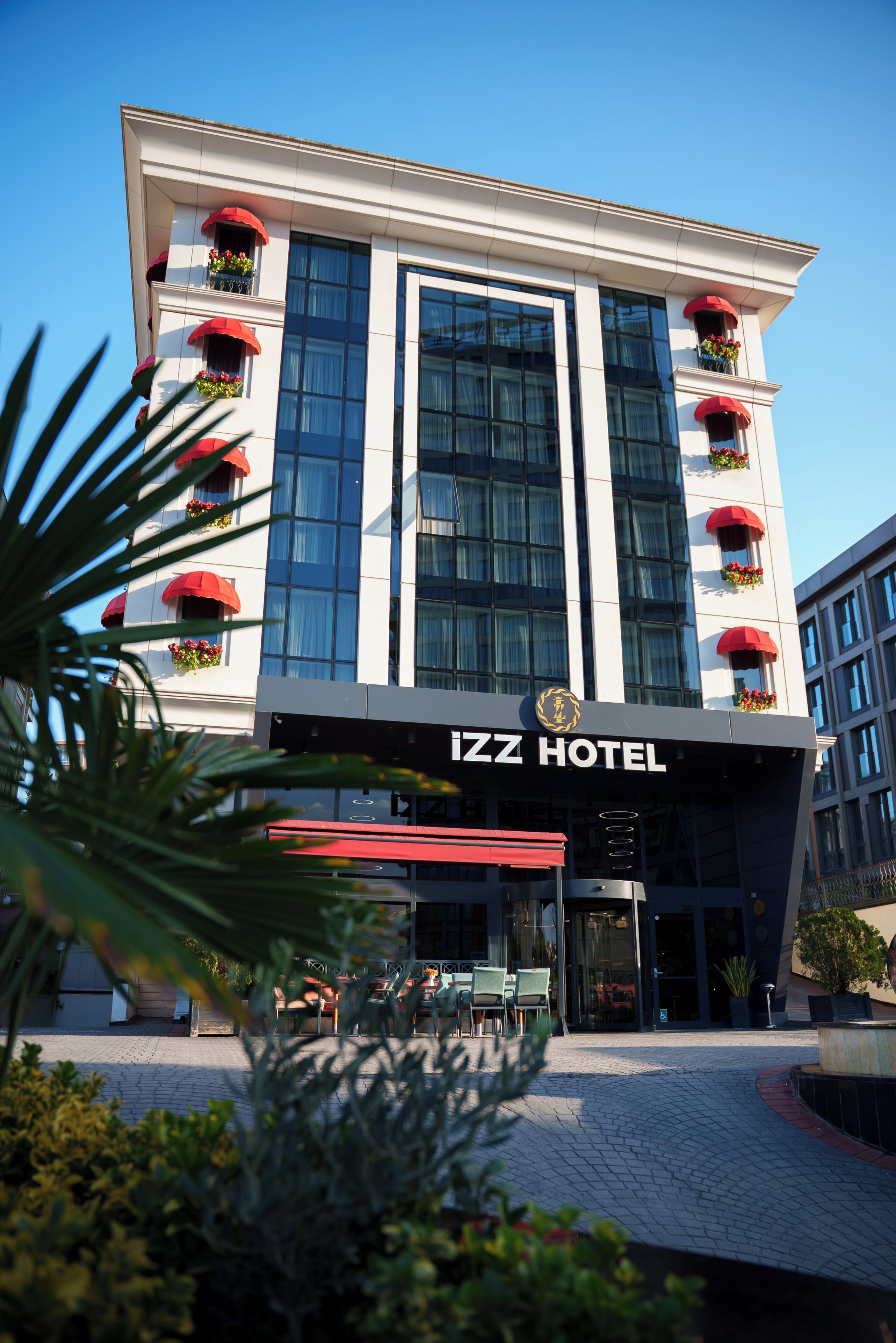Un hotel moderno con una entrada destacada, ventanas amplias y toldos rojos.