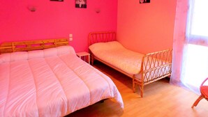 A room with two beds, a small table, and a window with curtains.