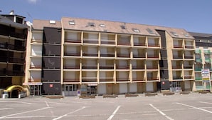 Un immeuble à plusieurs étages avec un parking situé devant.
