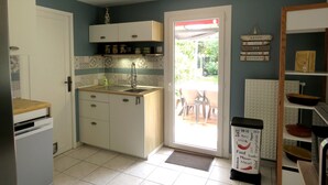 A compact kitchen with white cabinets, a sink, and a countertop. There is a door leading to a patio area with outdoor seating. - Pleasant bright house with terrace and garden (Plaisance-du-Touch)