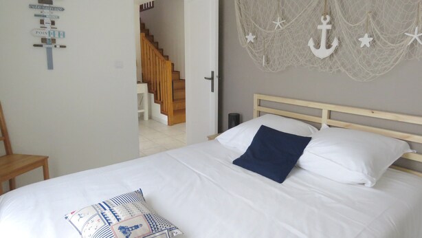 A bedroom with a bed, a wooden headboard, a wall-mounted anchor decoration, and a staircase in the background. - Pleasant bright house with terrace and garden (Plaisance-du-Touch)