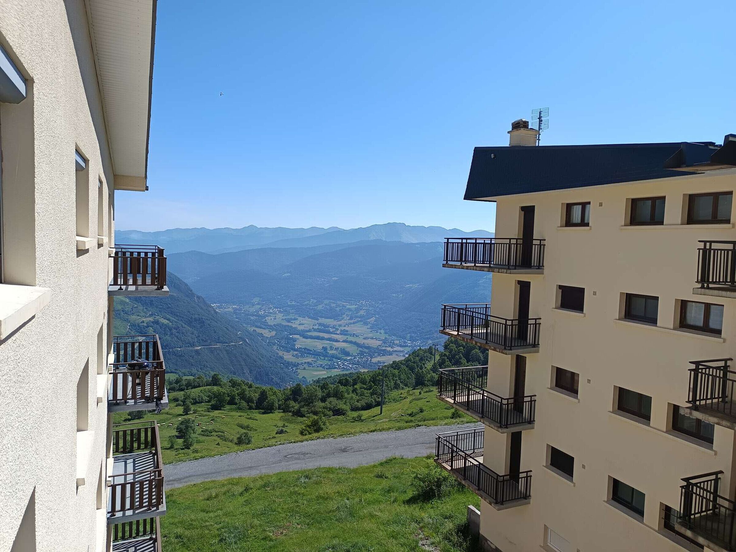 A multi-story building with balconies overlooking a mountainous landscape.