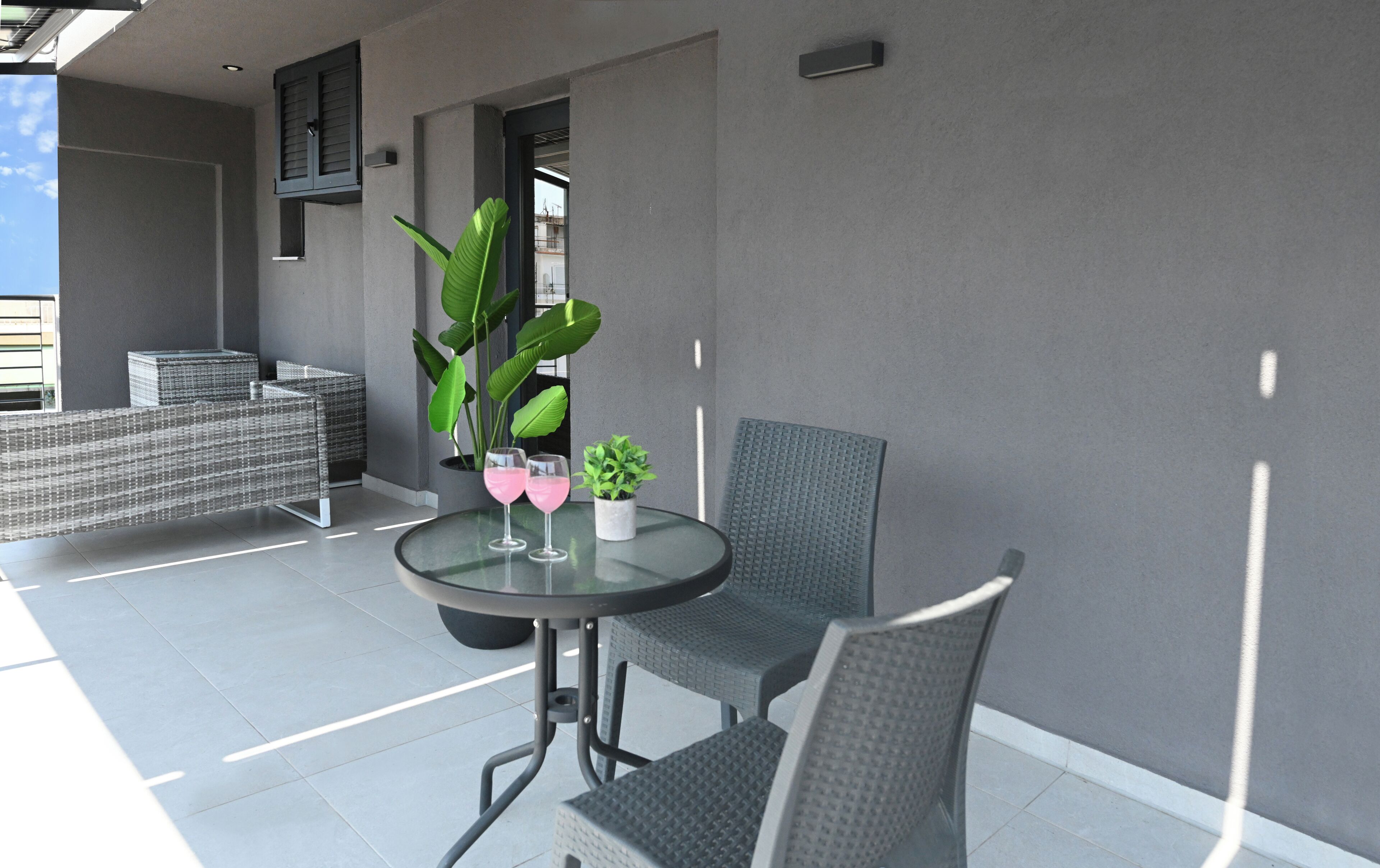 A modern outdoor seating area with a round table, two chairs, and potted plants.