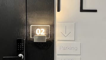 A door with a digital lock and a keypad, a wall-mounted sign with the letters "FL", and a sign indicating "Parking" and "Laundry Room" below.