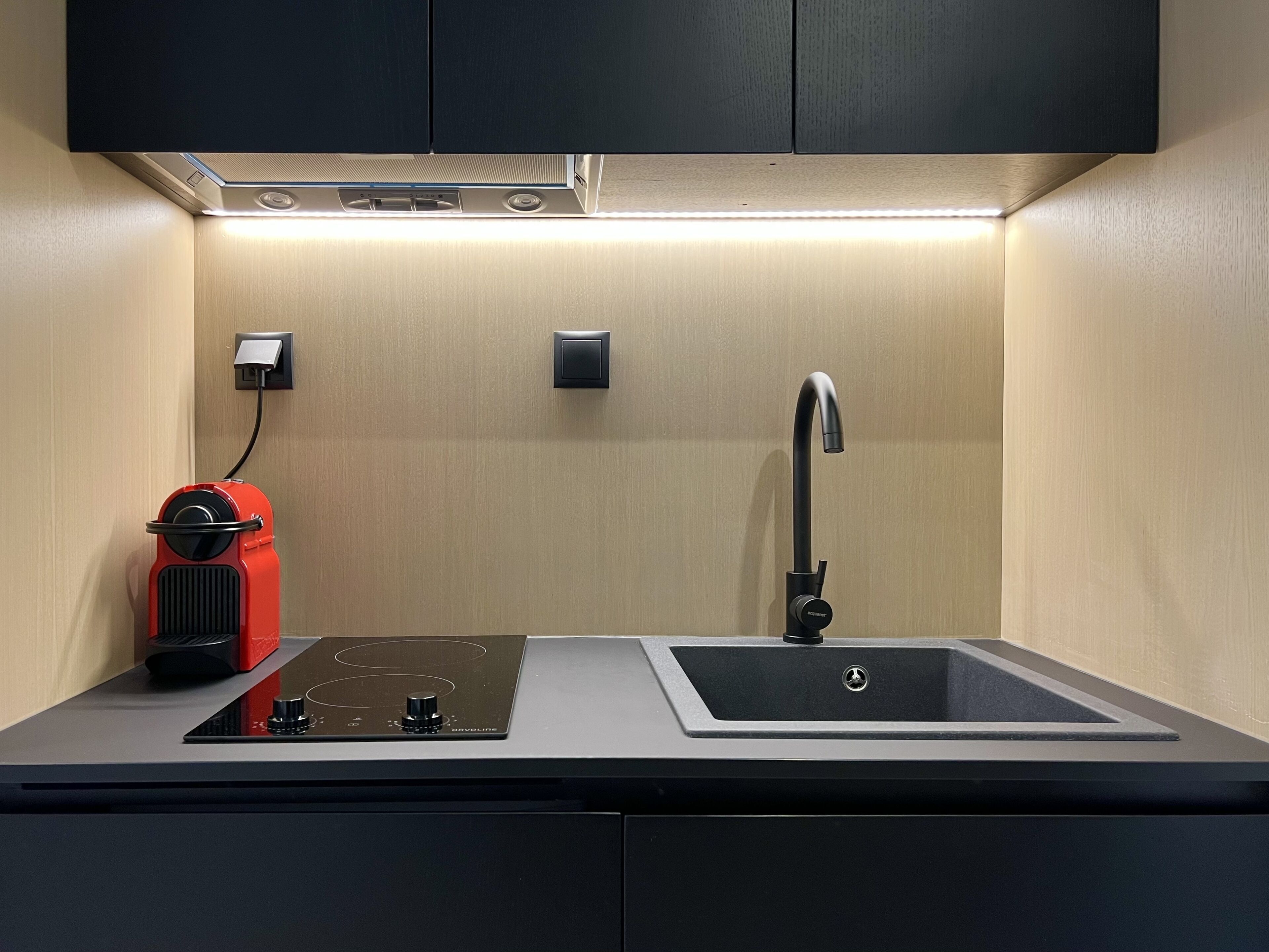 A modern kitchen with a built-in stove, a sink, and a compact coffee maker.