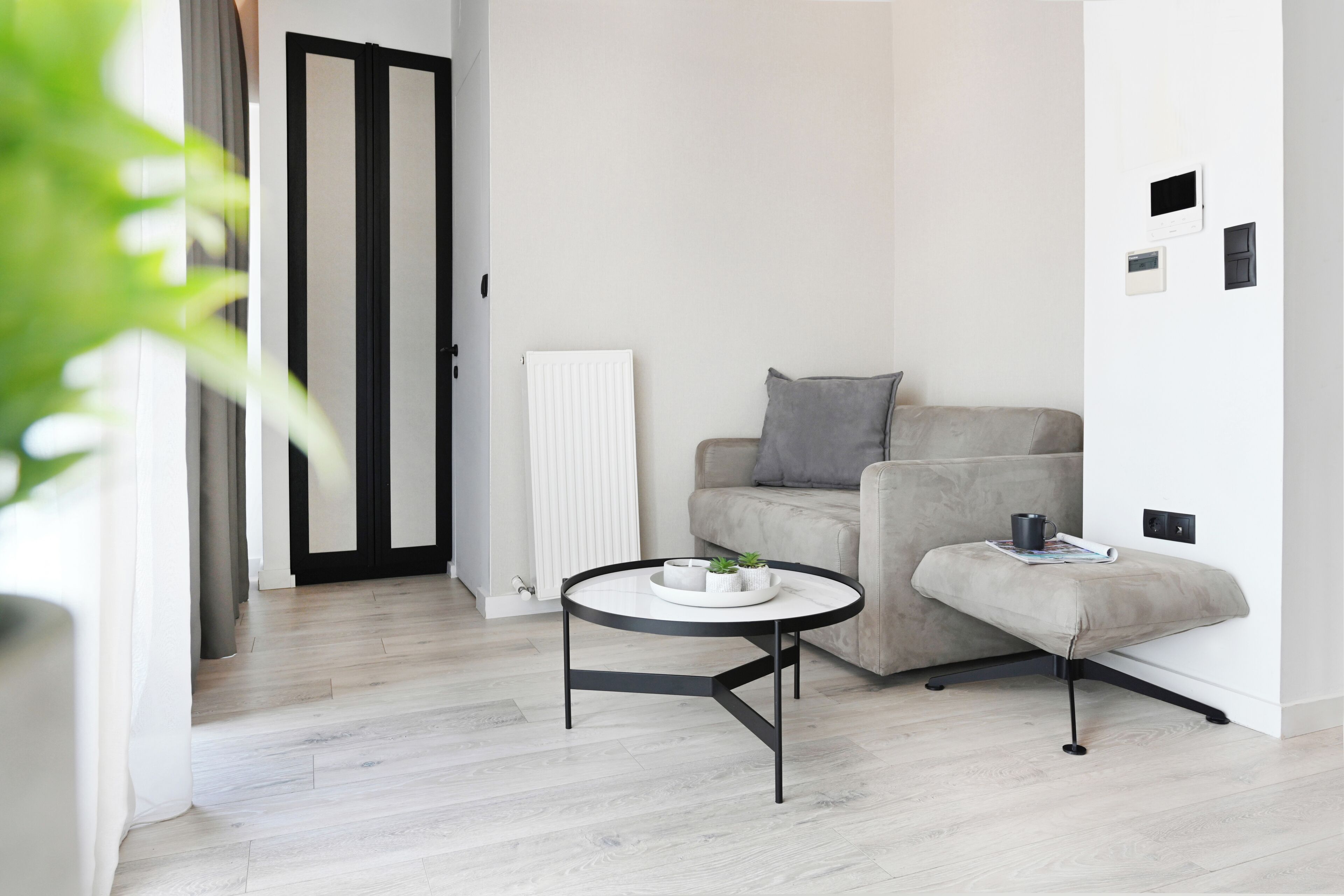 Ein modernes Wohnzimmer mit einem runden Tisch, einem grauen Sofa und einem kleinen Hocker.