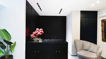 Un intérieur moderne avec un meuble noir, un fauteuil beige et une plante en pot.