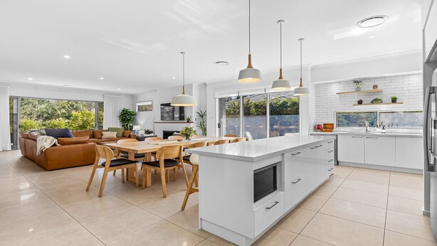 A modern kitchen with a central island, white cabinetry, and pendant lighting. - Que Syrah - 5 bedroom house with 4 bathrooms (POKOLBIN)