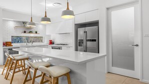 A modern kitchen with a large island, stainless steel appliances, and pendant lighting. - Que Syrah - 5 bedroom house with 4 bathrooms (POKOLBIN)