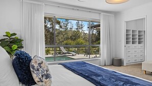 A bedroom with a large window, a bed, a blue throw, and a storage unit. - Que Syrah - 5 bedroom house with 4 bathrooms (POKOLBIN)