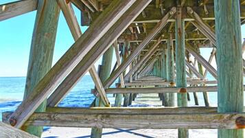 A wooden pier structure with a clear view of the ocean and beach.