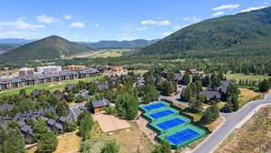 Zona residencial con varias casas, una cancha de tenis y montañas al fondo.