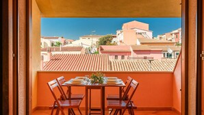 A balcony with a table set for four, overlooking a residential area with terracotta-tiled roofs. - Beach front apartment (Sant.Teresa di Gallura)