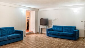 A living room with two blue sofas, a television on a stand, and a lamp. - Beach front apartment (Sant.Teresa di Gallura)