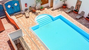 A rooftop pool with a blue border, surrounded by potted plants and outdoor seating. - Beach front apartment (Sant.Teresa di Gallura)