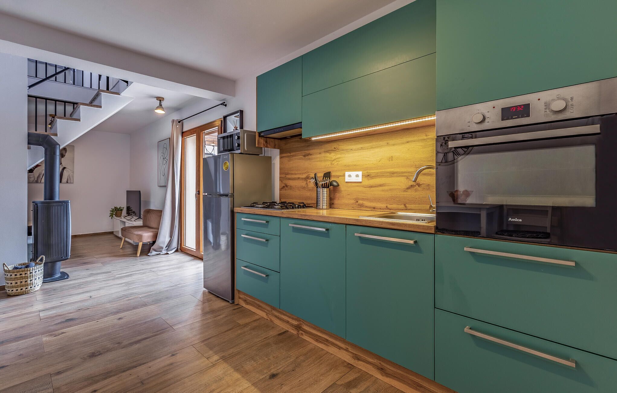 Une cuisine moderne avec des armoires de couleur turquoise, un réfrigérateur en acier inoxydable, un four à micro-ondes et un four traditionnel.