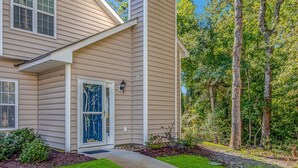 A two-story house with a front door, a small porch, and a landscaped garden with trees and shrubs. - Discount! Walk to Beach, Golf,  Pool, Arcade, Beautiful and peaceful community (North Myrtle Beach)