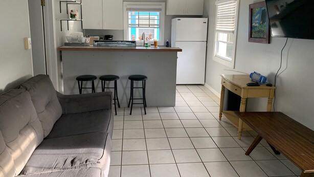 Un espacio habitable compacto con kitchenette, un sofá, una pequeña mesa de comedor y un televisor.