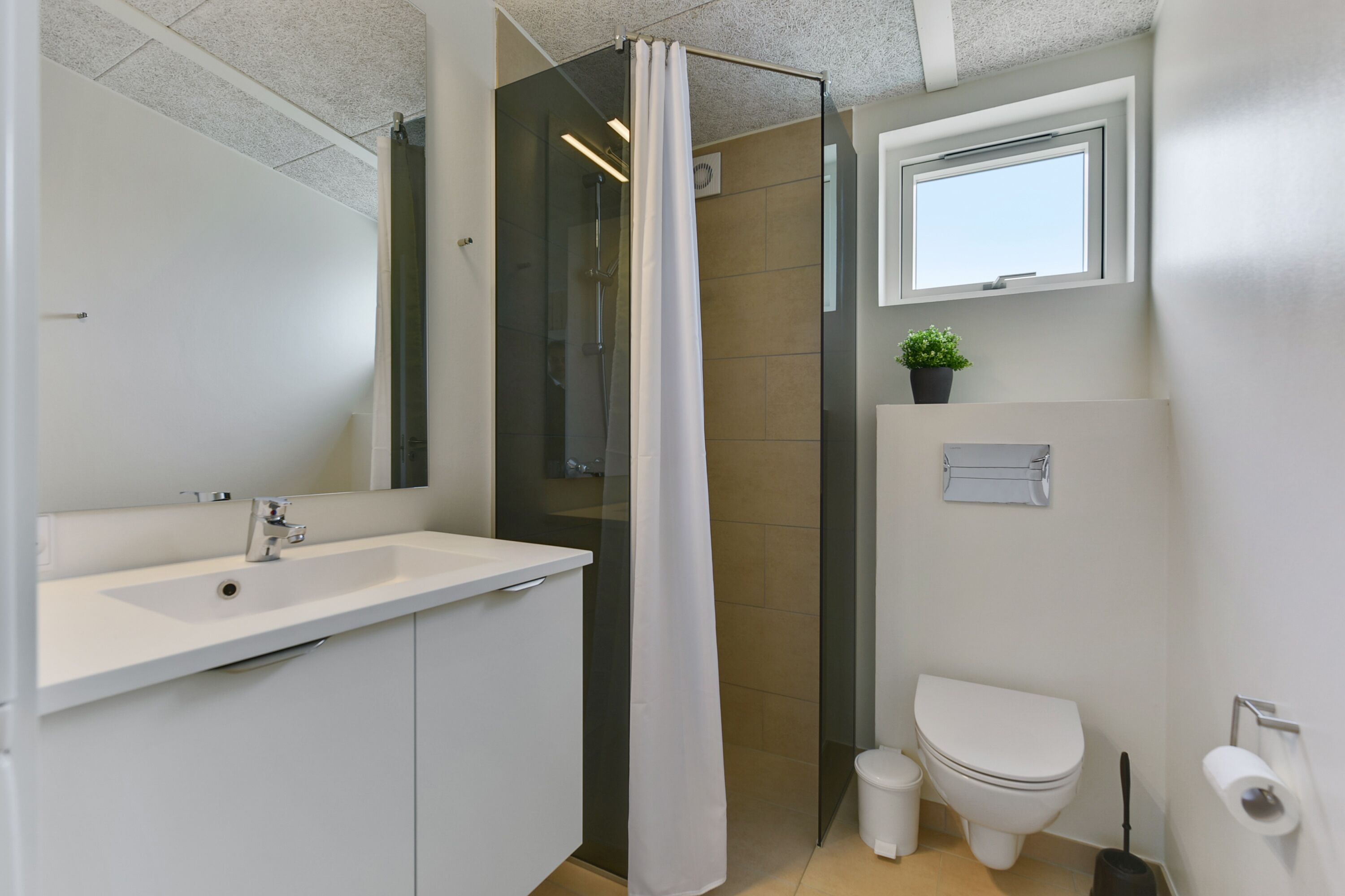 A modern bathroom with a glass shower enclosure, a white sink, and a toilet.