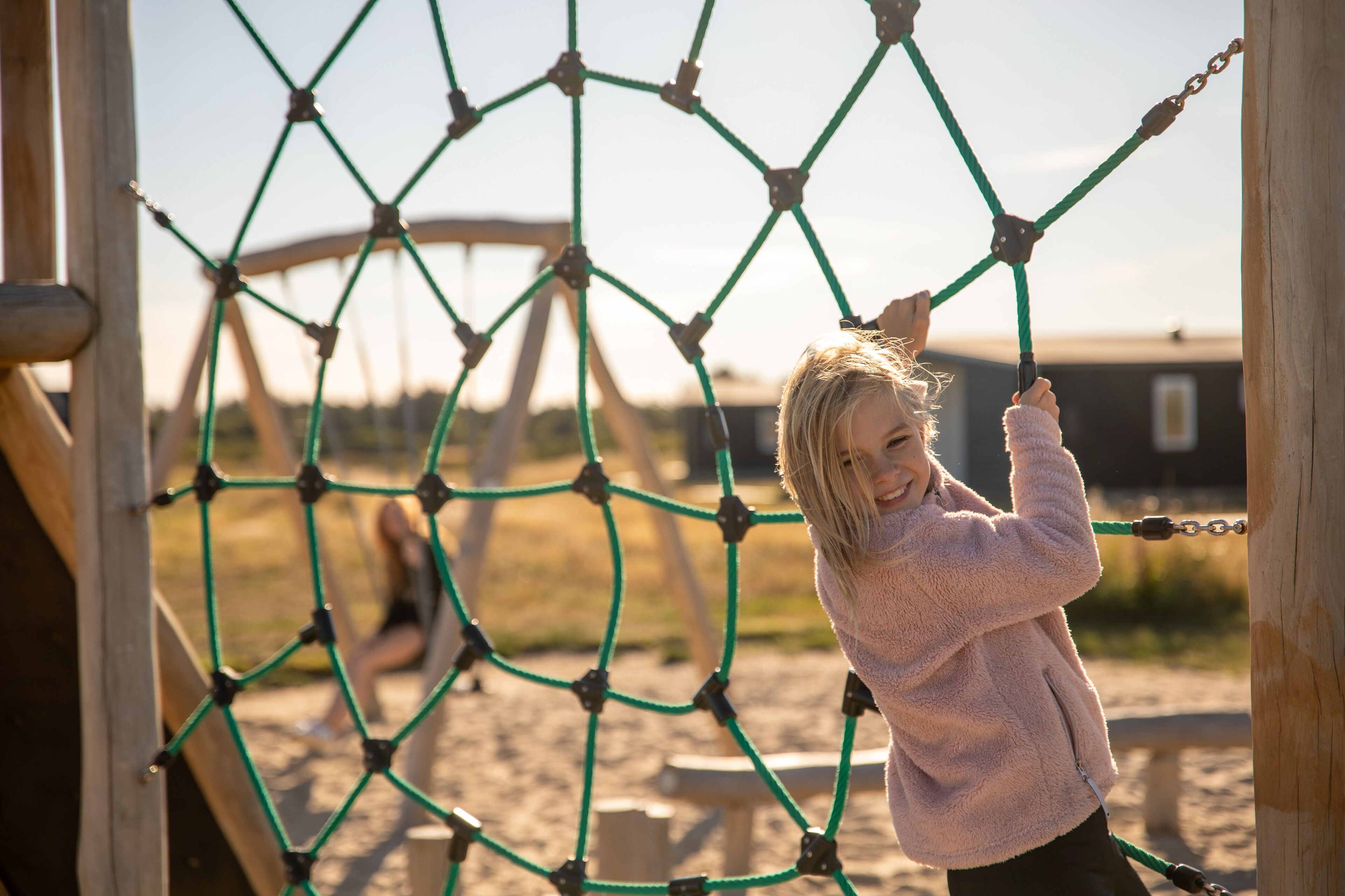 A child playing on a rope net structure at a playground.