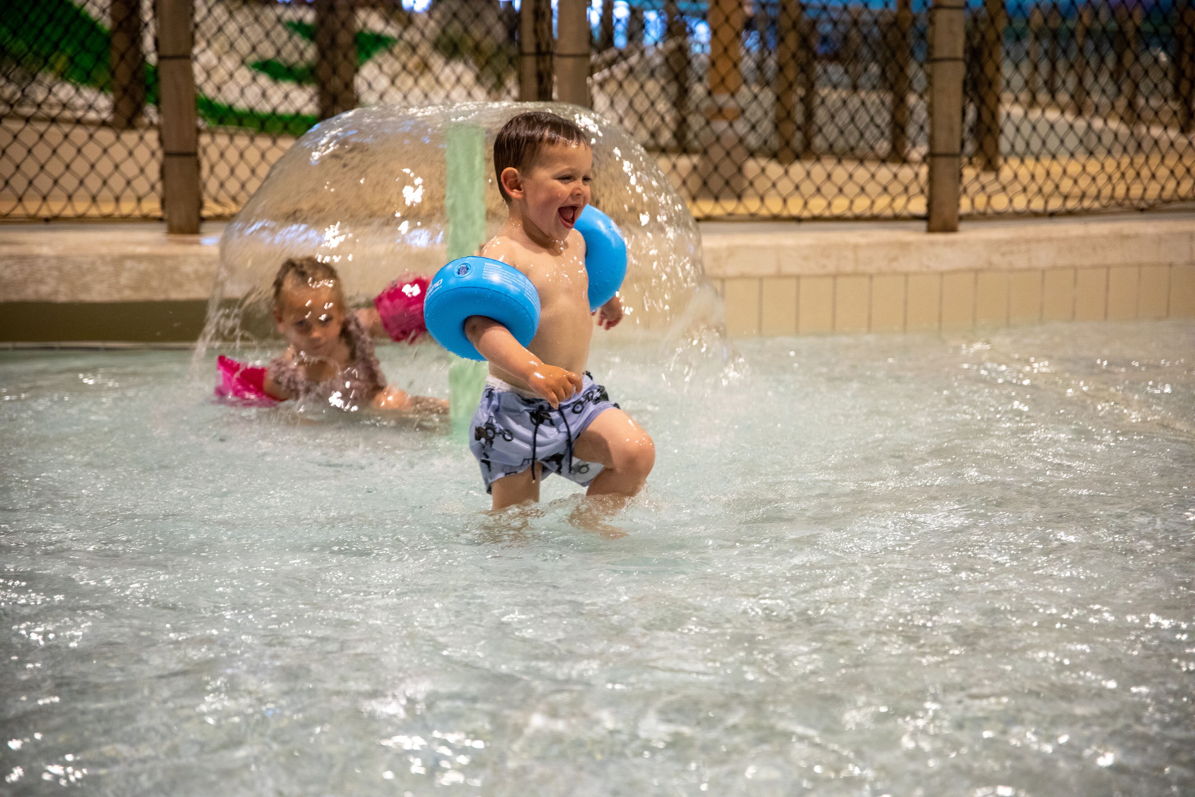 Ein Kind spielt in einem Wasserpark unter einer transparenten Kuppel.