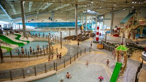 Parque acuático interior con múltiples piscinas, toboganes y zonas de juegos.