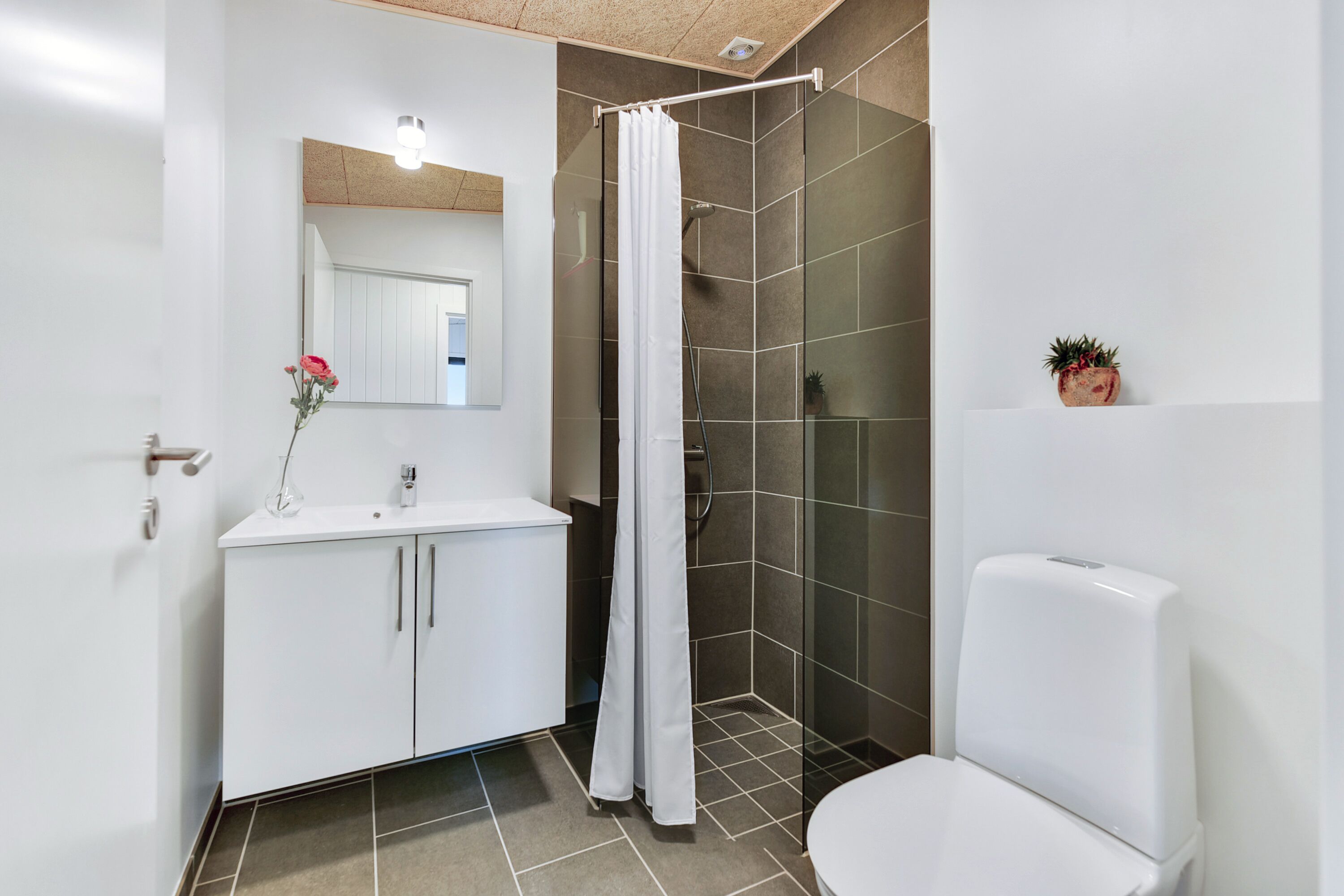 A modern bathroom with a shower, toilet, and sink.