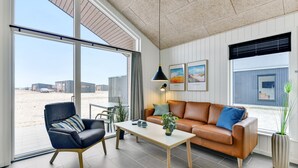 Un salon moderne avec une grande fenêtre, un canapé en cuir, un fauteuil bleu et une table basse.